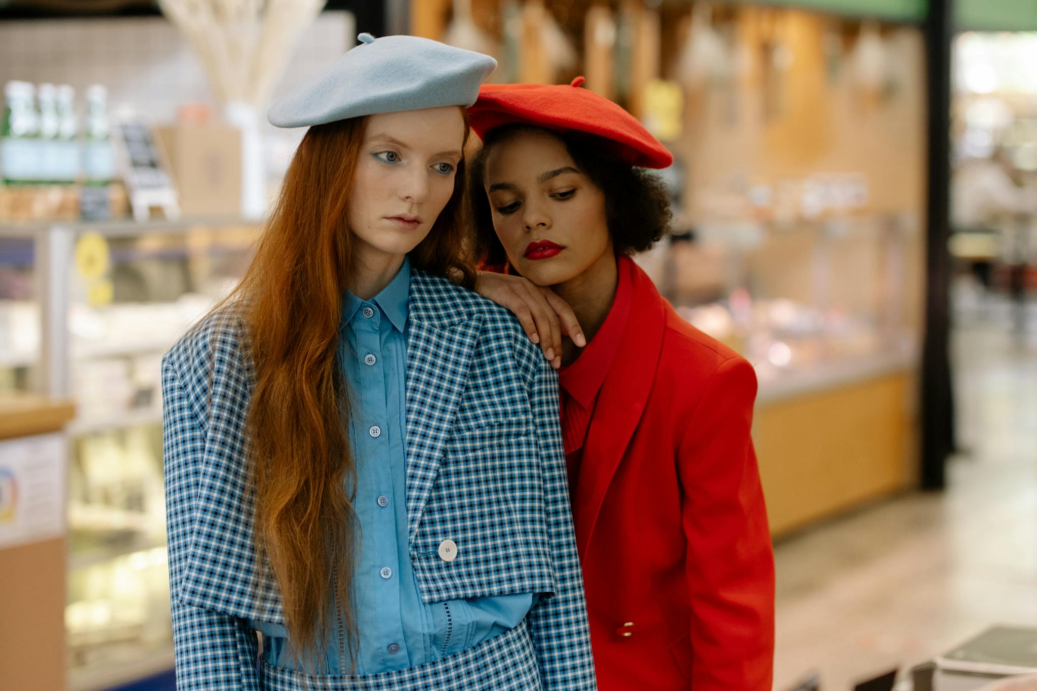 Two fashionable women wearing berets and chic outfits in a supermarket setting.